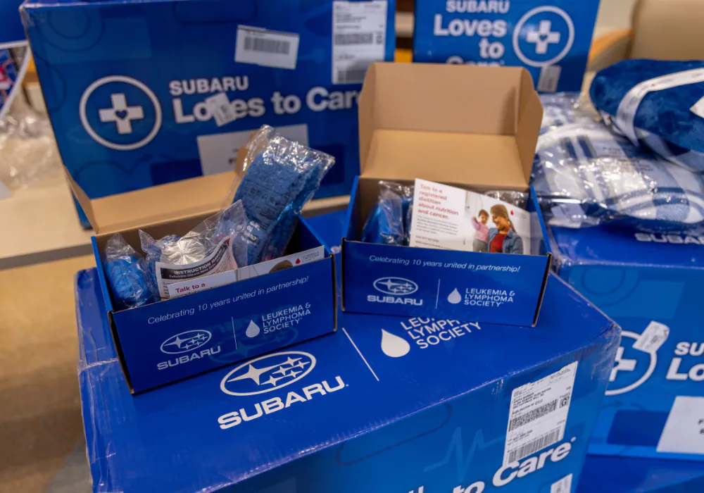 Subaru Loves to Care boxes with kits for Leukaemia & Lymphoma Society, including items and educational pamphlets.