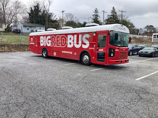 Red bus with BIG RED BUS written in white on its side, parked in a lot.
