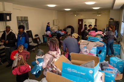 People, including adults and children, sort through donated clothes from 